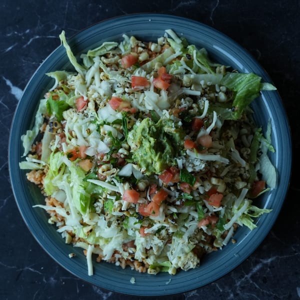 El Fuego Mexican Grill's vibrant salad bowl with lettuce, corn, tomatoes, cheese, and guacamole.