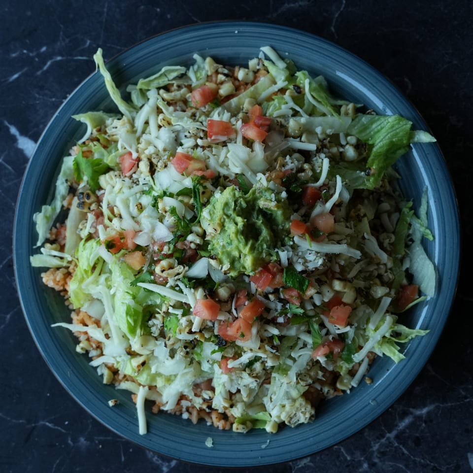 El Fuego Mexican Grill's vibrant salad bowl with lettuce, corn, tomatoes, cheese, and guacamole.