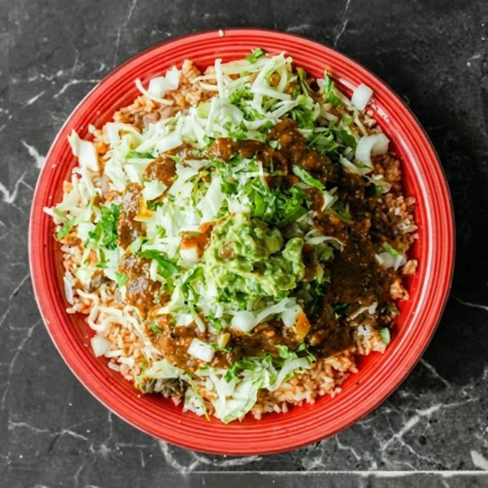 A vibrant red plate filled with rice, topped with shredded cabbage, salsa, and guacamole.