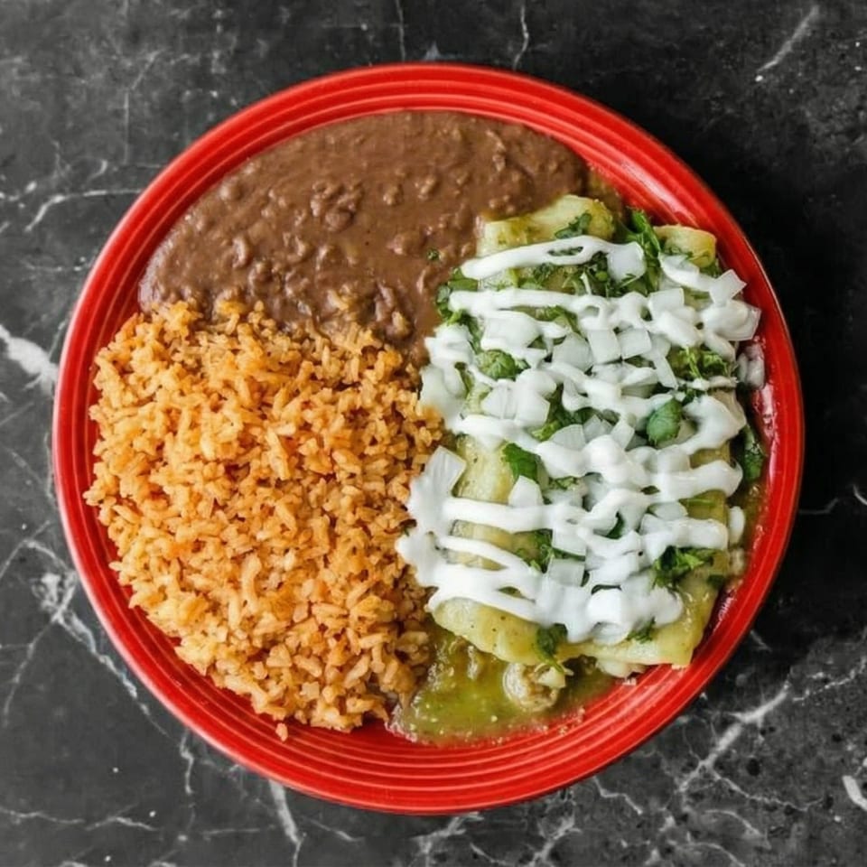 A red plate with green enchiladas, refried beans, and Spanish rice on a dark marble surface.